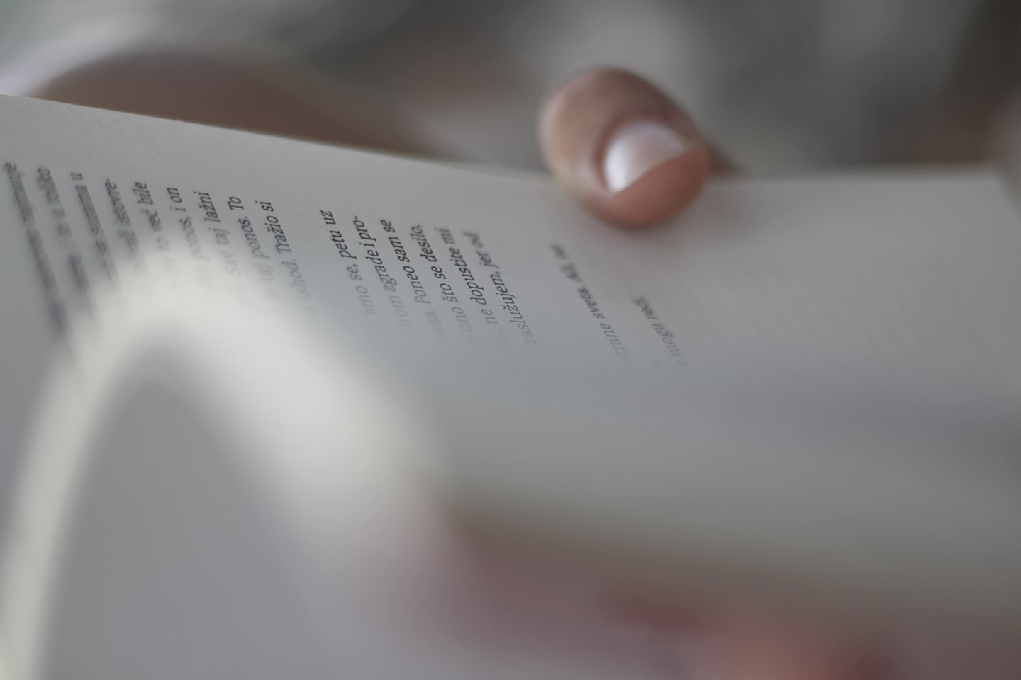 Hand turning a page in a white book.